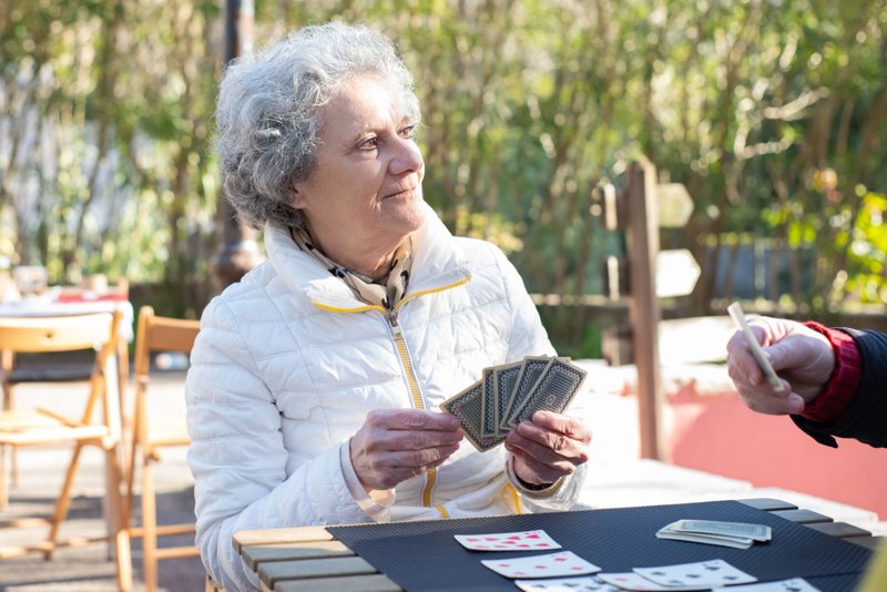 Donna anziana che gioca a carte all&rsquo;aperto