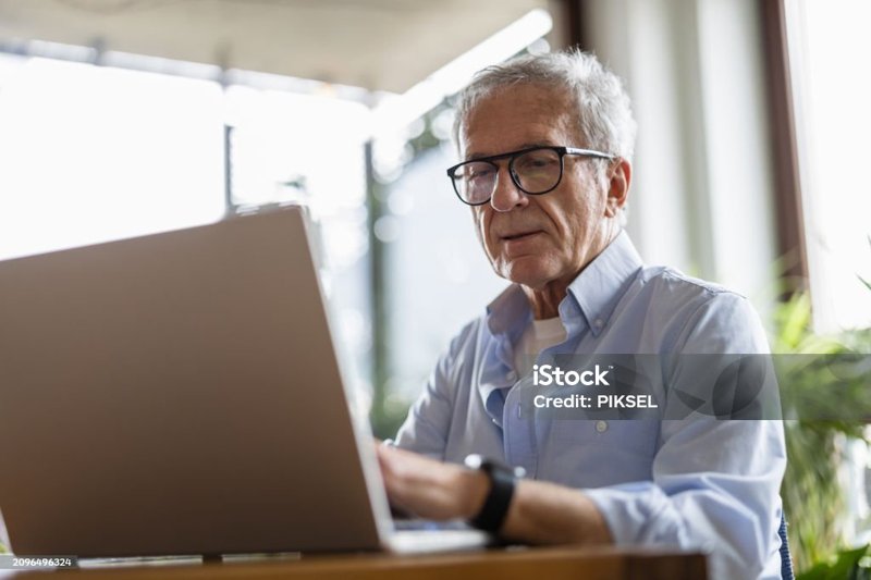 Uomo anziano che lavora al computer portatile